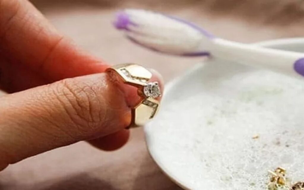 Ngâm nhẫn trong nước ấm pha nước rửa chén 1–2 tiếng (hoặc qua đêm), rồi dùng bàn chải mềm chải sạch các kẽ